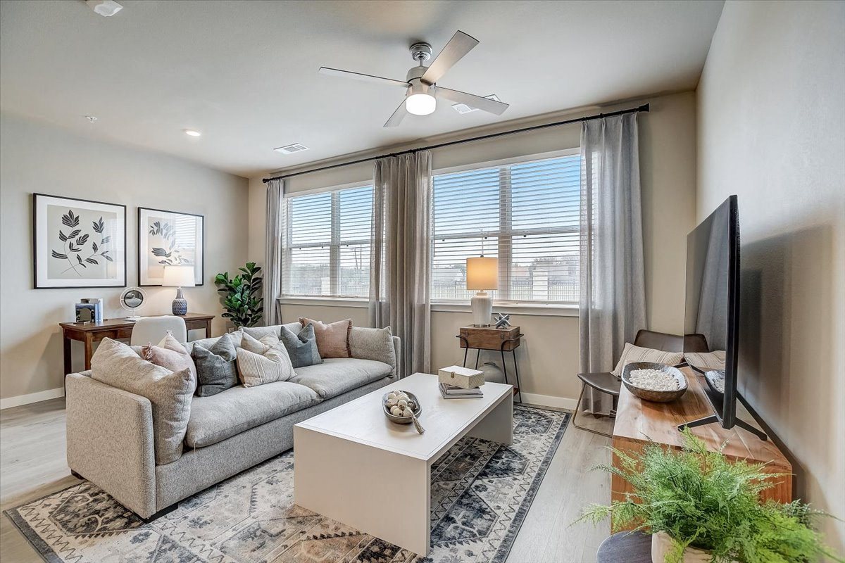 Cozy living room with oversized windows, patterned area rug, and TV console for relaxing.